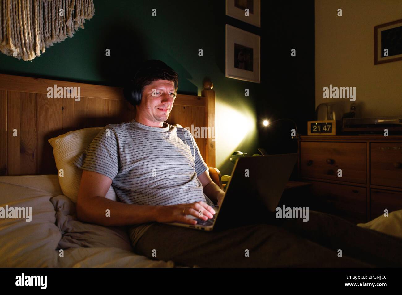 Man using laptop sitting on bed at home Stock Photo