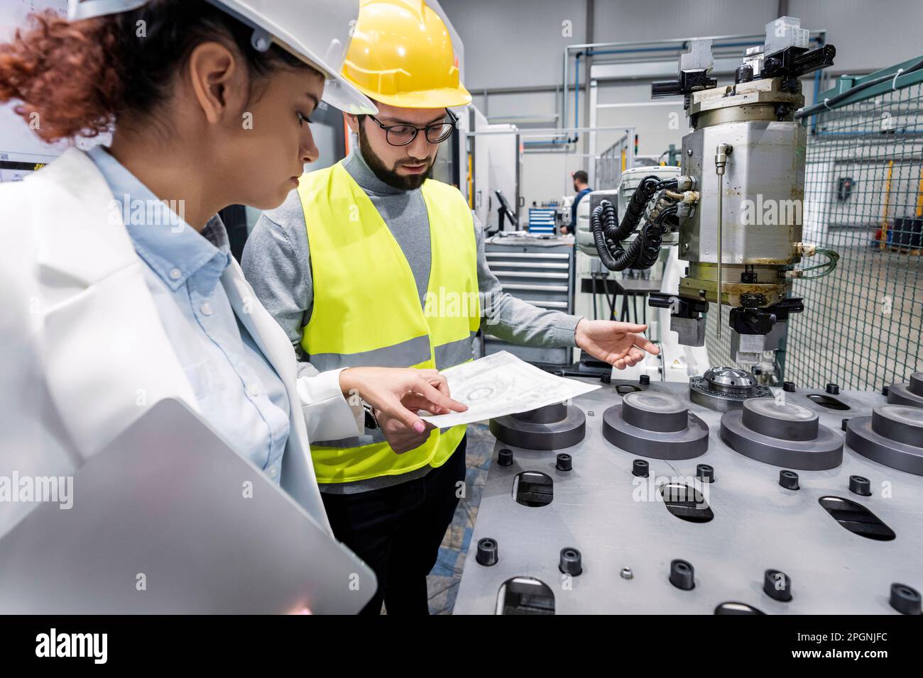 Engineer and colleague checking blueprint in factory Stock Photo