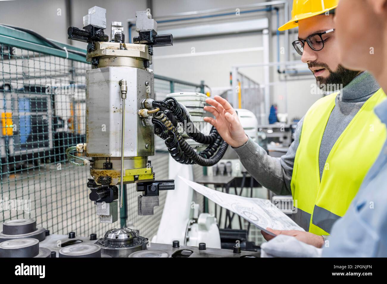 Engineer with blueprint explaining colleague in factory Stock Photo