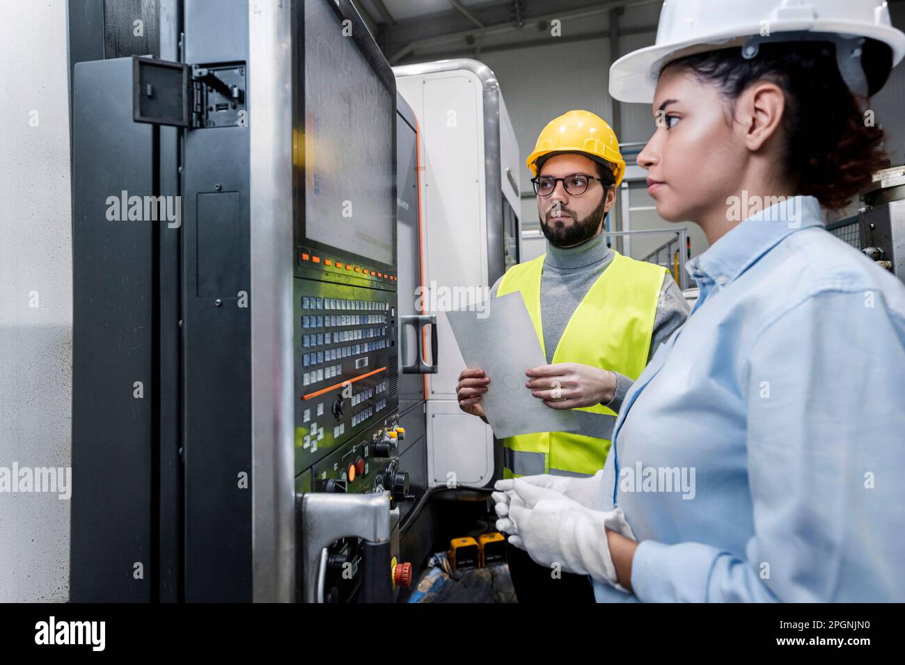 Business people working on machine controls in factory Stock Photo