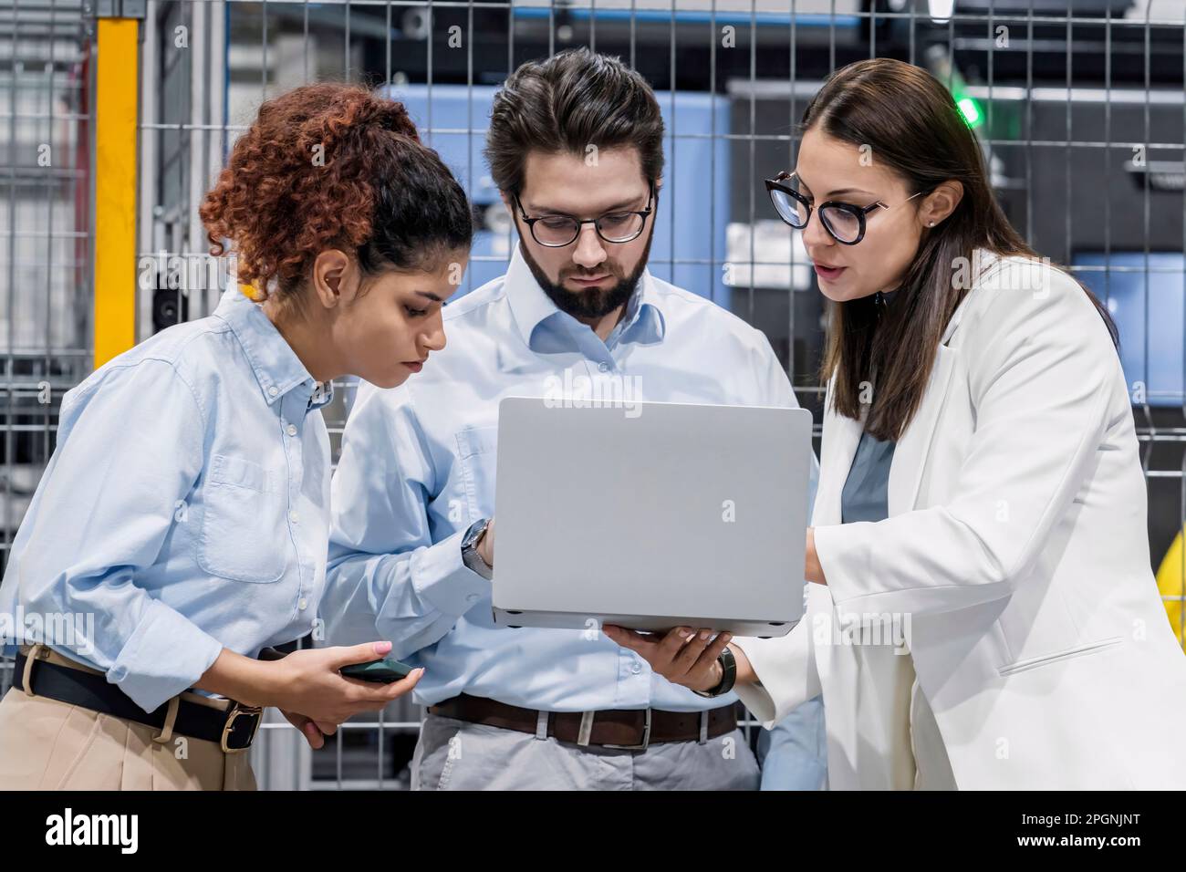 Businesswoman sharing laptop with colleagues in factory Stock Photo