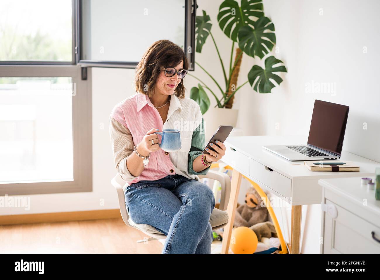 Smiling freelancer using smart phone at home Stock Photo