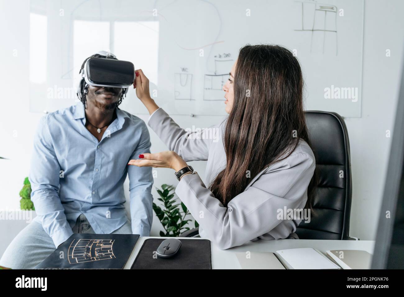Architect adjusting virtual reality headset for colleague sitting at ...