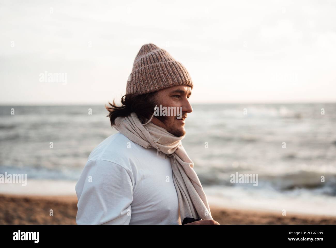 Man wearing knit hat standing in front of sea at beach Stock Photo