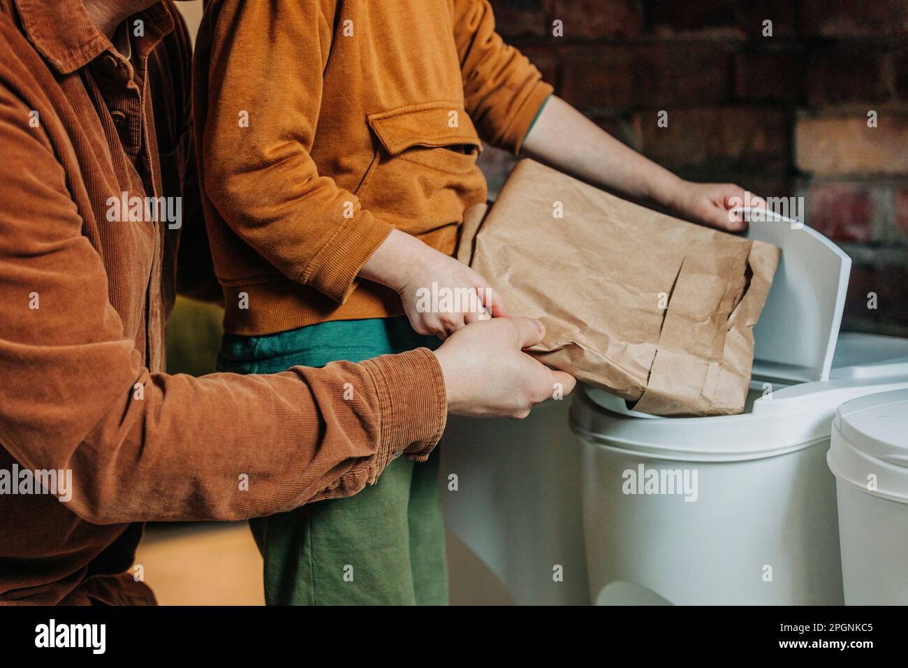 Father teaching son to throw garbage in recycling dustbin at home Stock