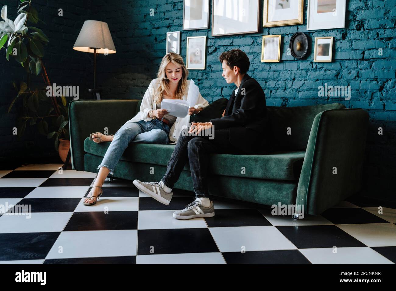Actress reading script sitting with producer on sofa at film set Stock Photo