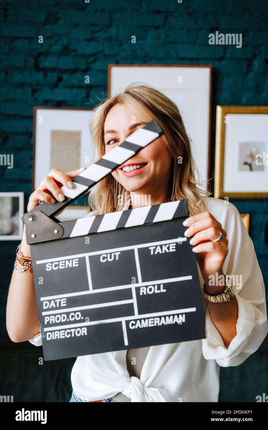 Smiling actress holding clapboard on film set Stock Photo