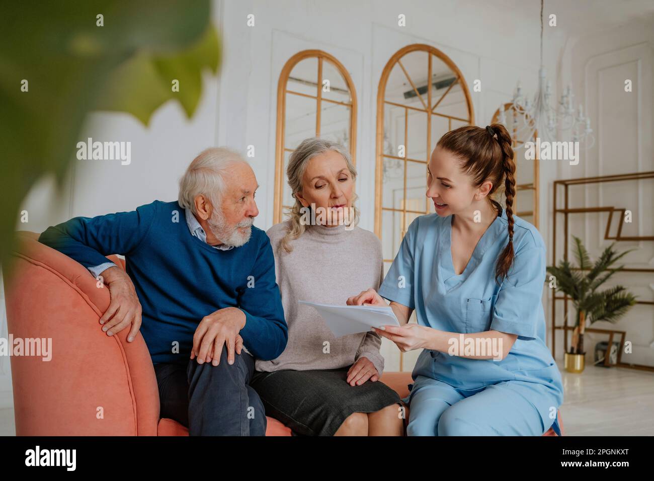 Happy nurse explaining medical reports to senior man and woman at home Stock Photo