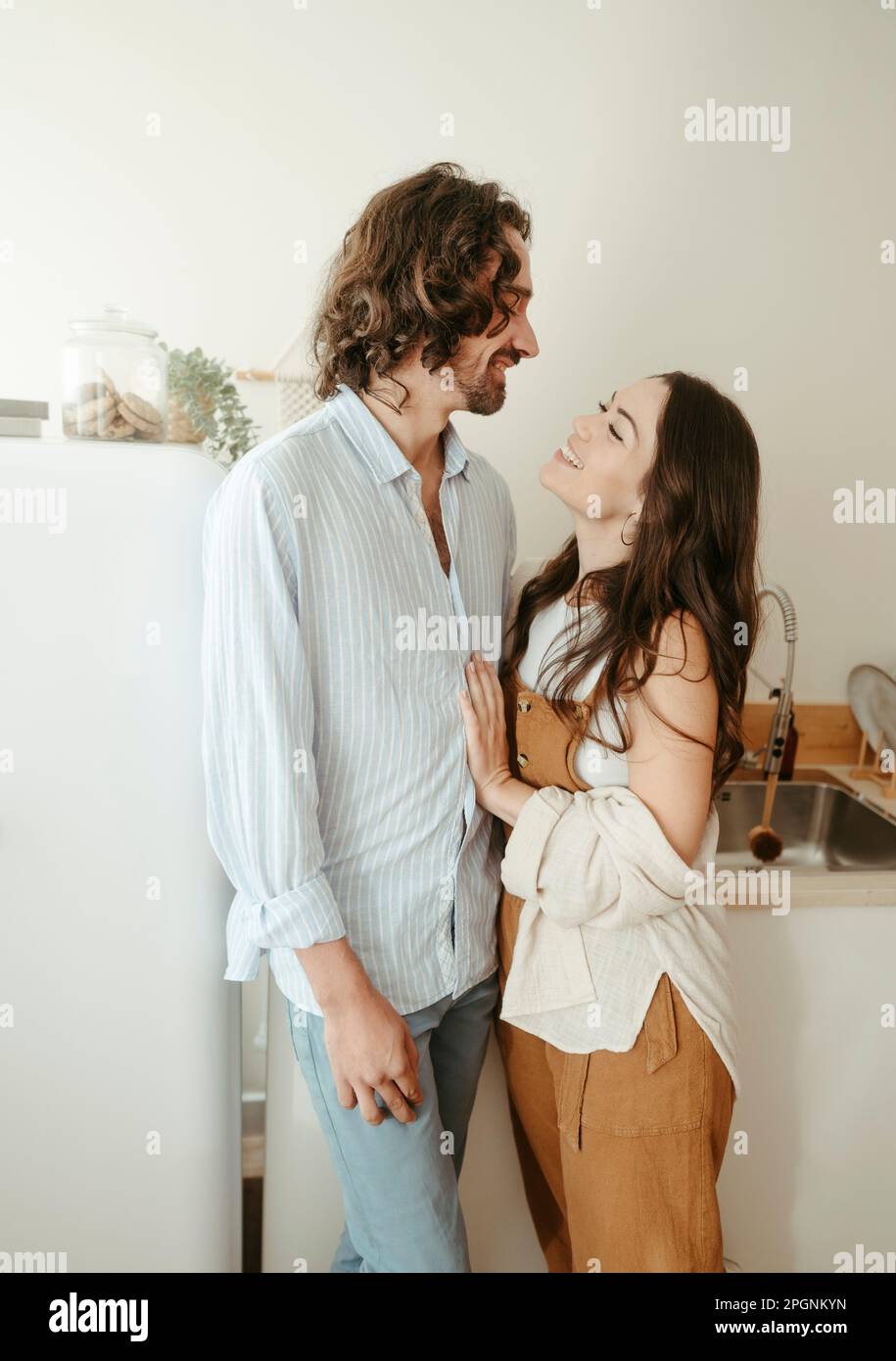 Happy couple looking at each other standing in kitchen Stock Photo