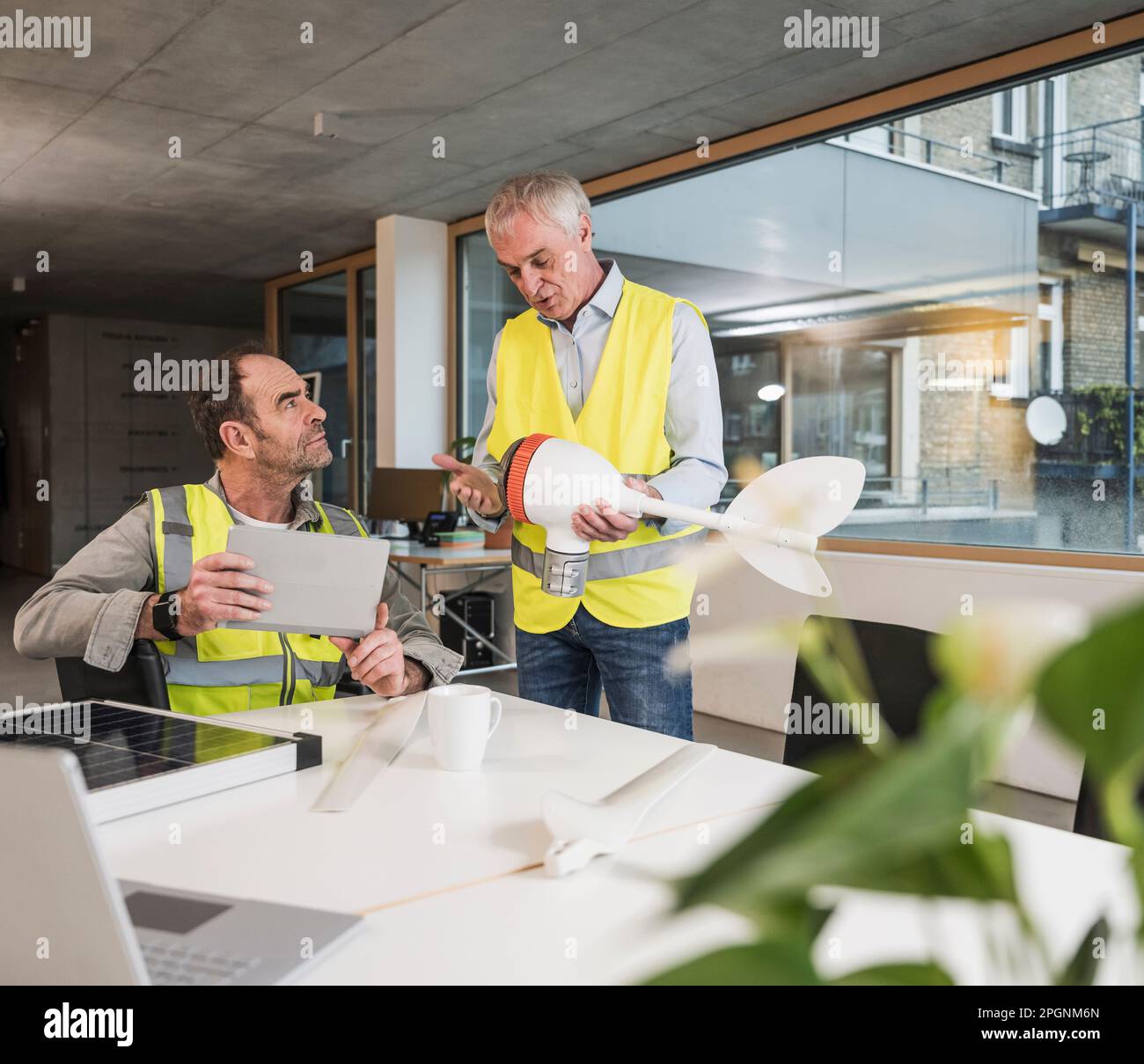 Engineers discussing over wind turbine rotor at office Stock Photo