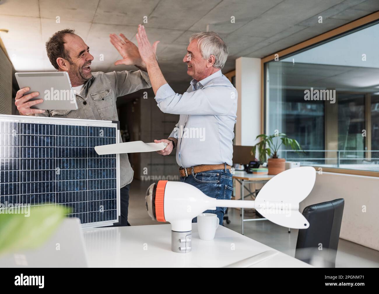 Business colleagues giving high-five standing at office Stock Photo - Alamy