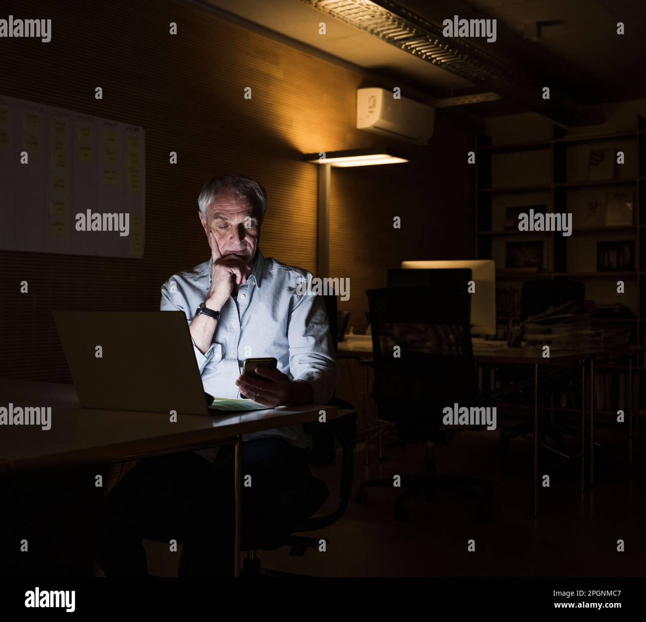 Businessman using smart phone sitting at office Stock Photo