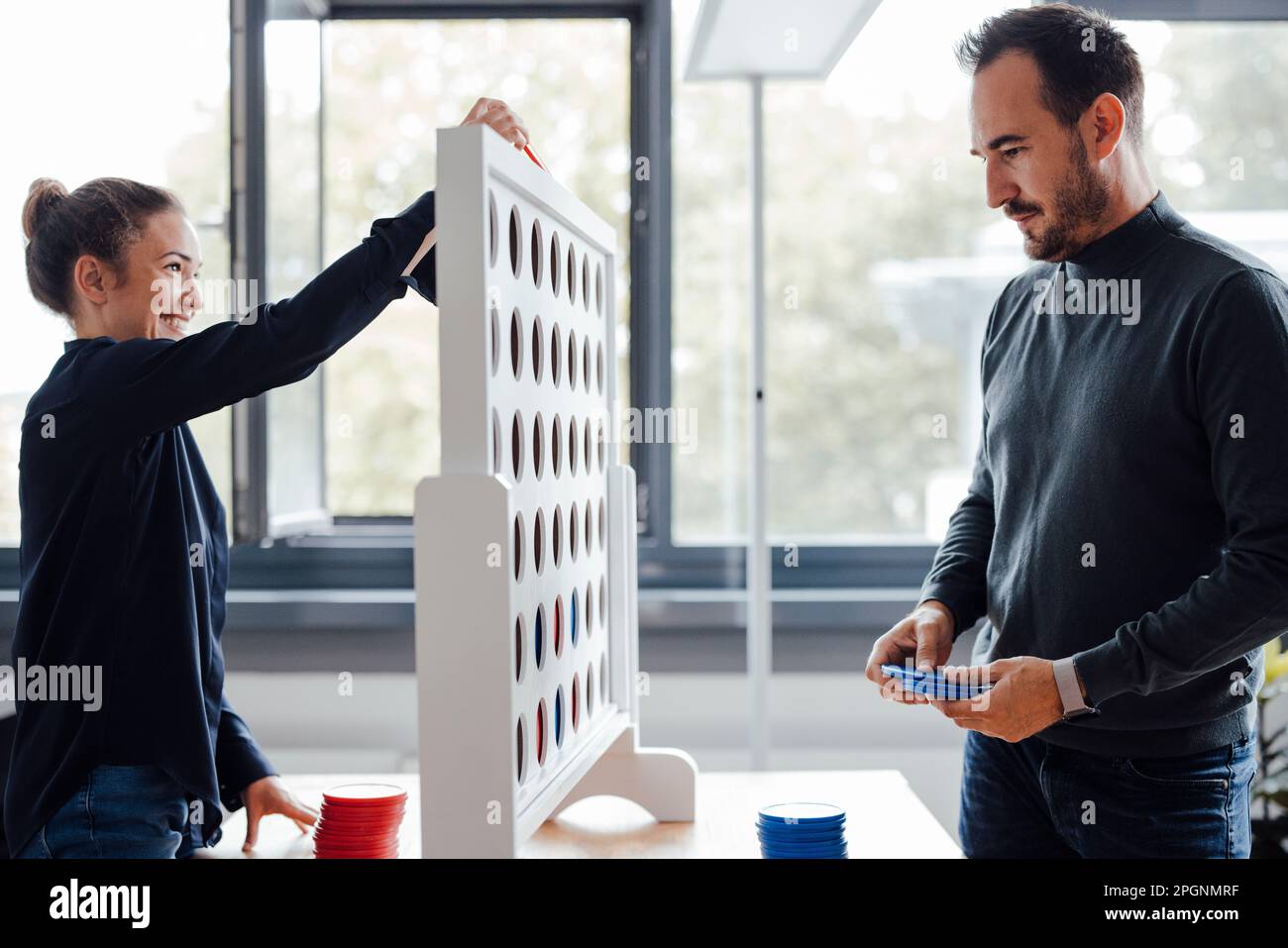 Happy businesswoman with colleague playing connect four dots game in office Stock Photo