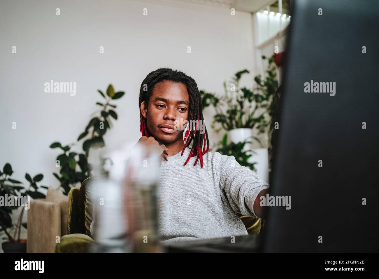 Thoughtful freelancer sitting with laptop at home office Stock Photo