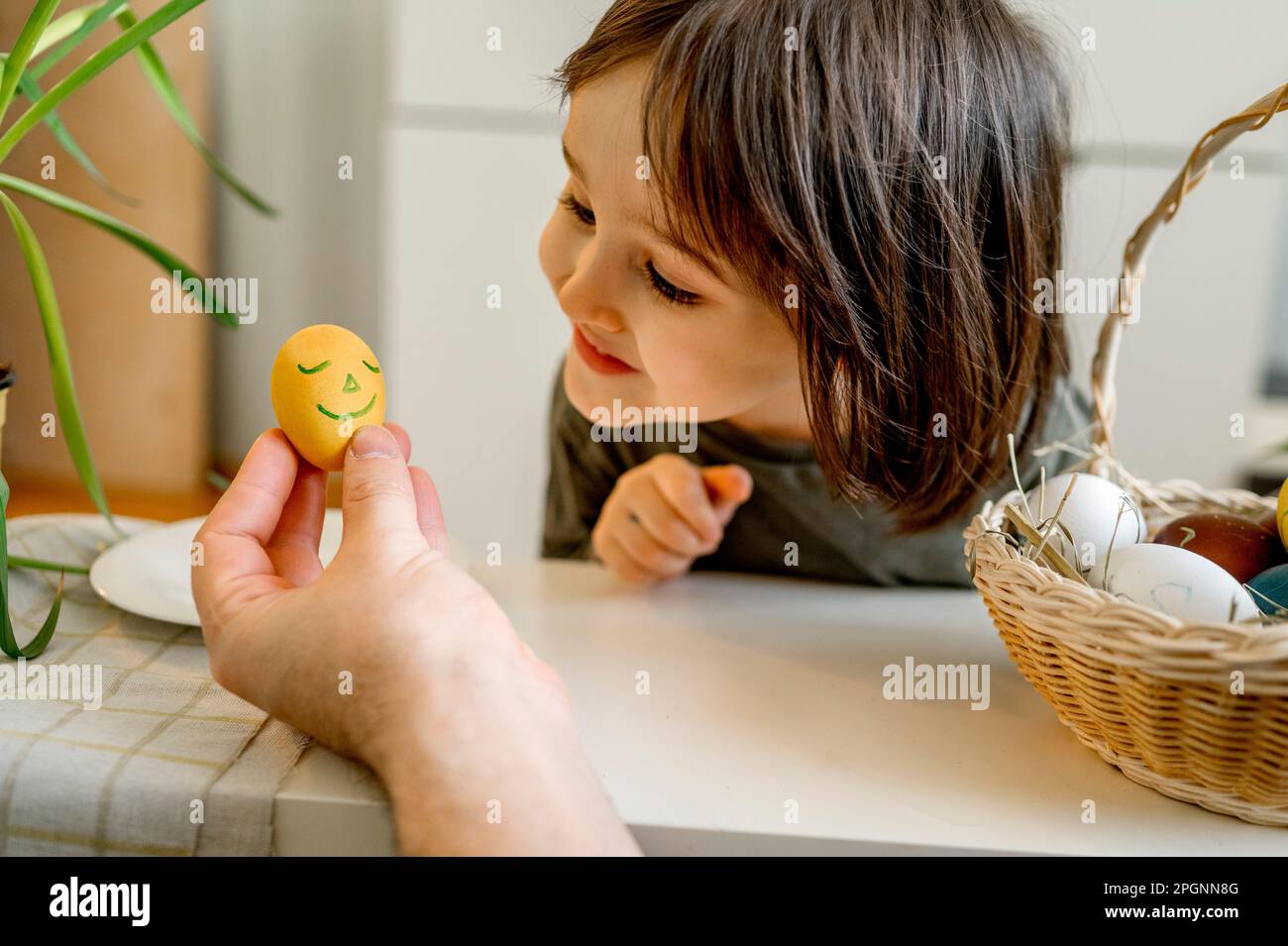Smiling boy looking at decorated Easter egg at home Stock Photo