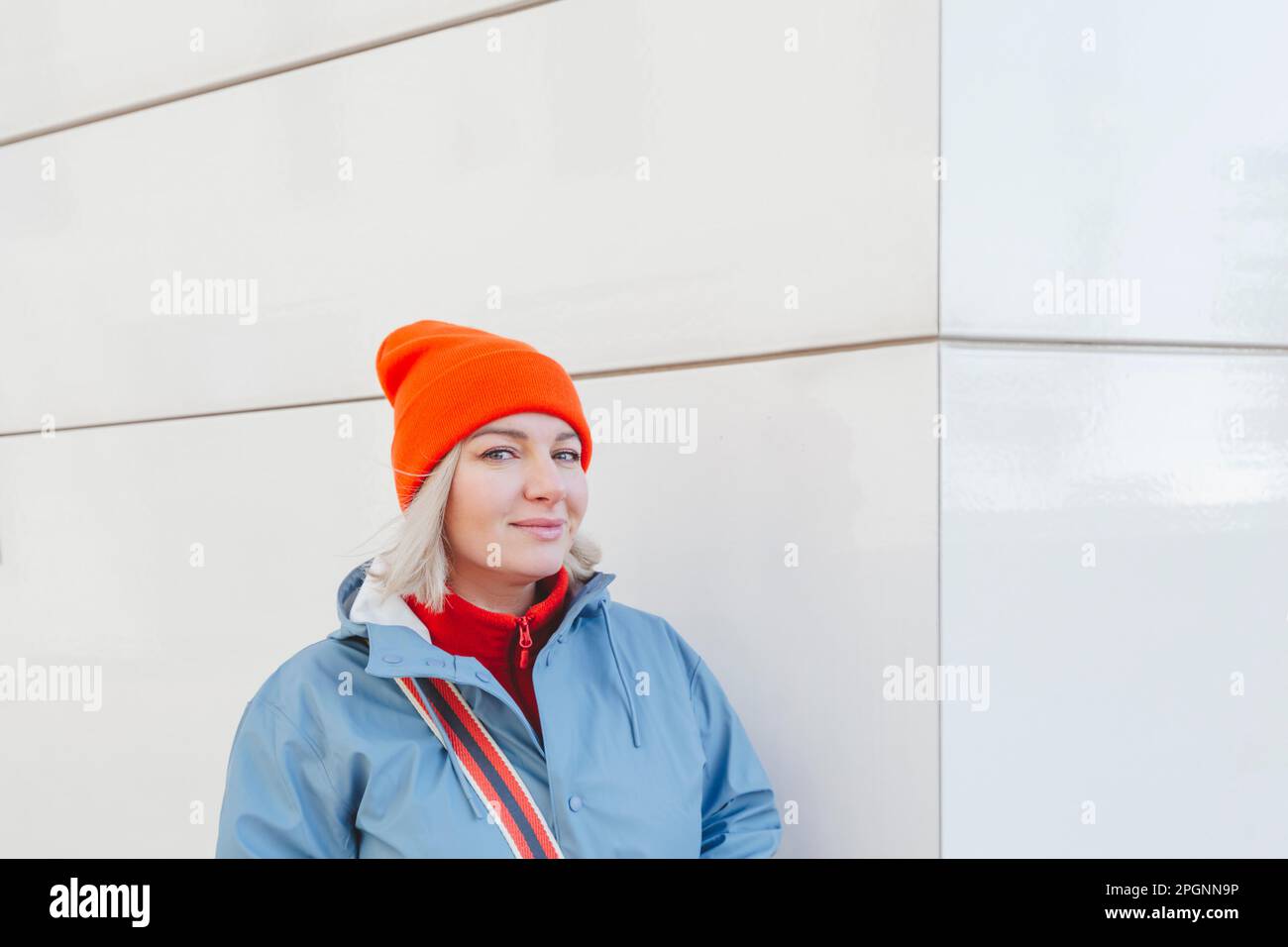 Smiling woman wearing knit hat near wall Stock Photo