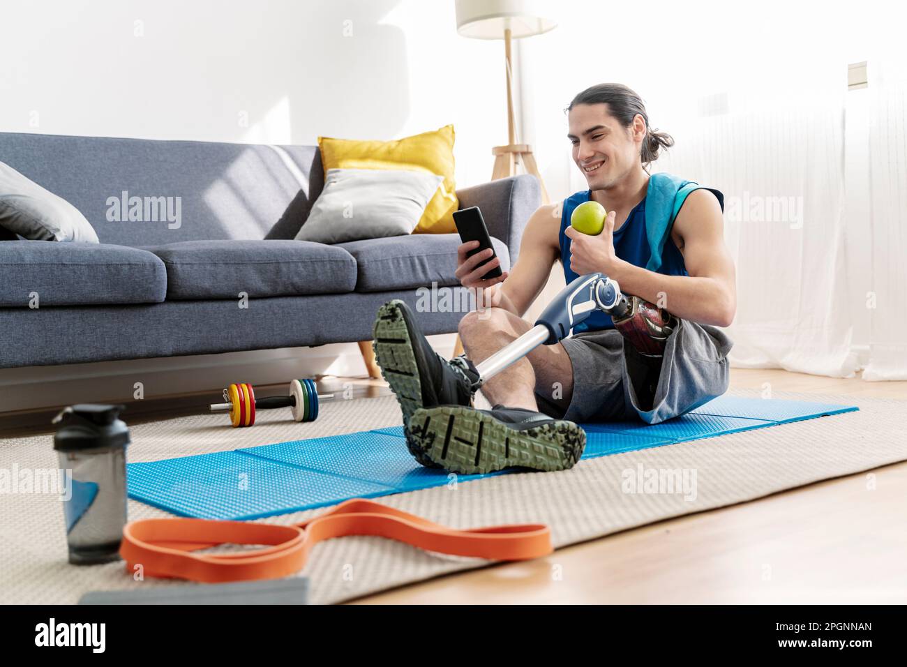 Smiling young man with disability using smart phone sitting at home Stock Photo