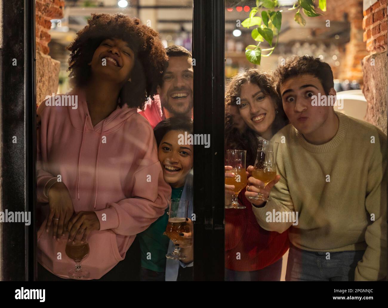Young friends holding drinks having fun seen through glass Stock Photo