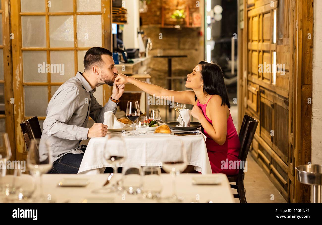 Young man kissing girlfriend's hand at restaurant Stock Photo