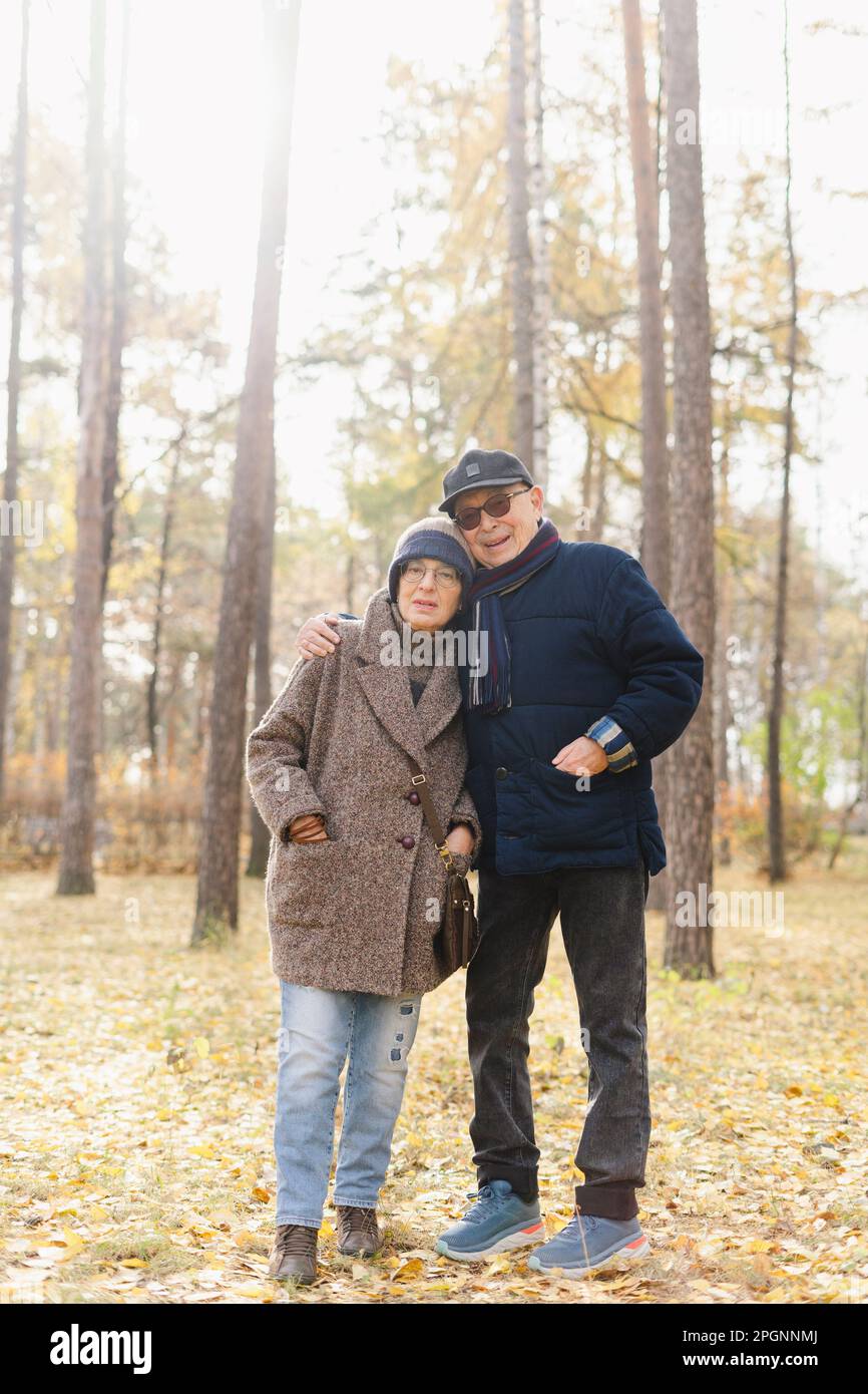 Senior man with arm around woman standing at park Stock Photo