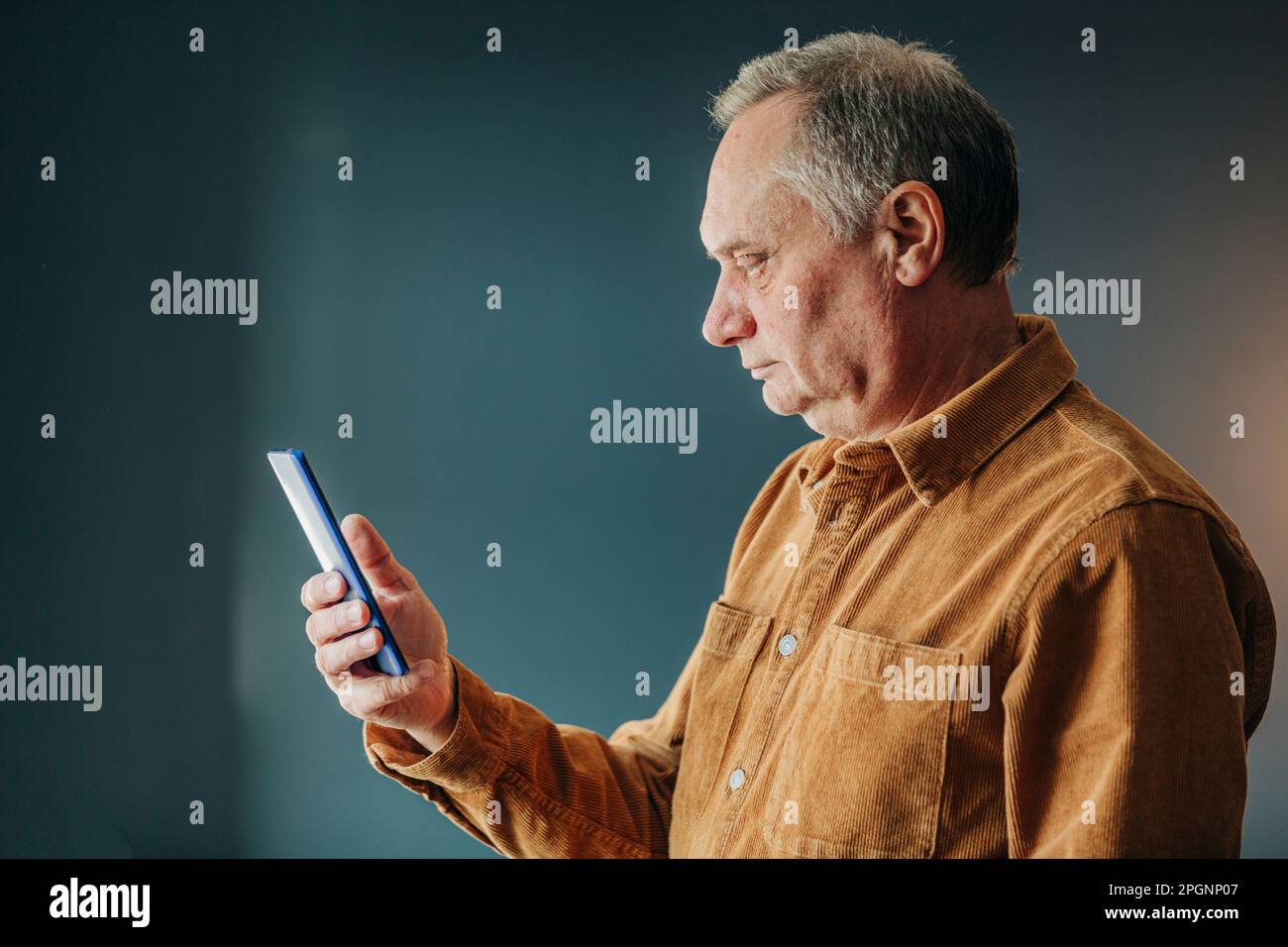 Senior man using smart phone by wall Stock Photo