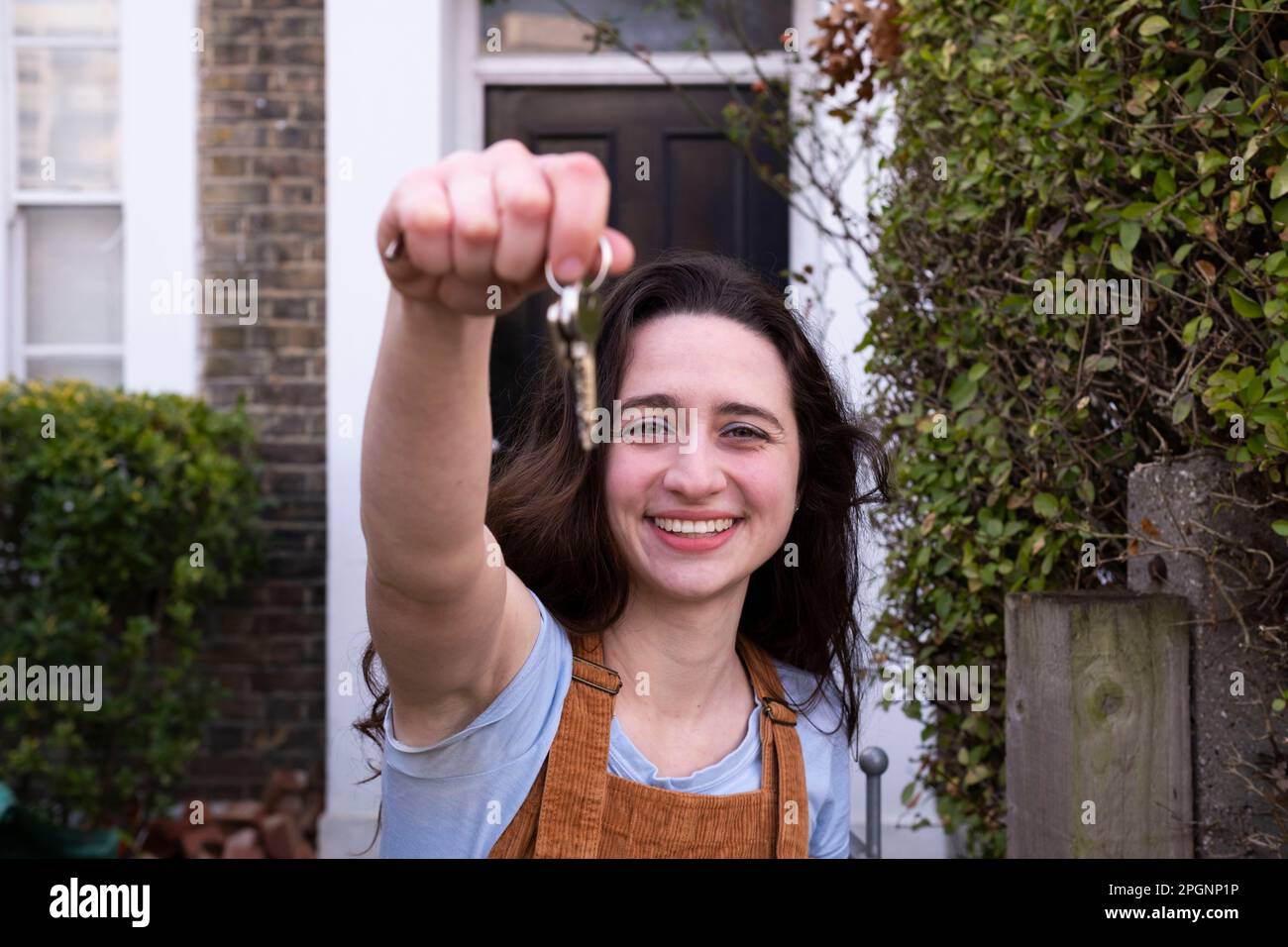 Smiling young woman holding keys of new house Stock Photo - Alamy