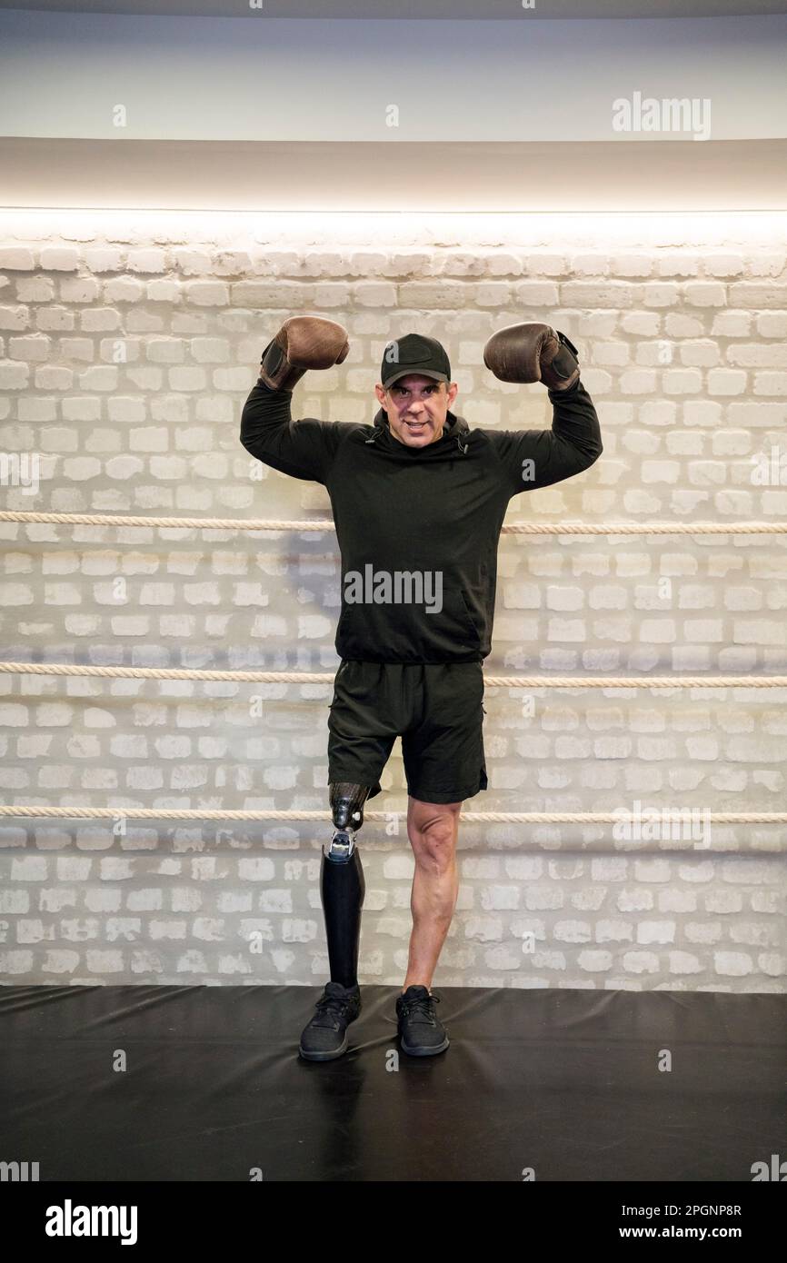 Confident man with artificial limb flexing muscles in gym Stock Photo