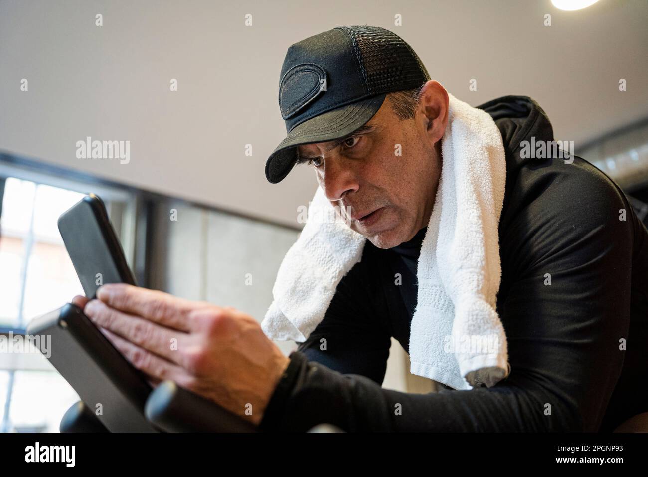 Focused man wearing cap using smart phone in gym Stock Photo
