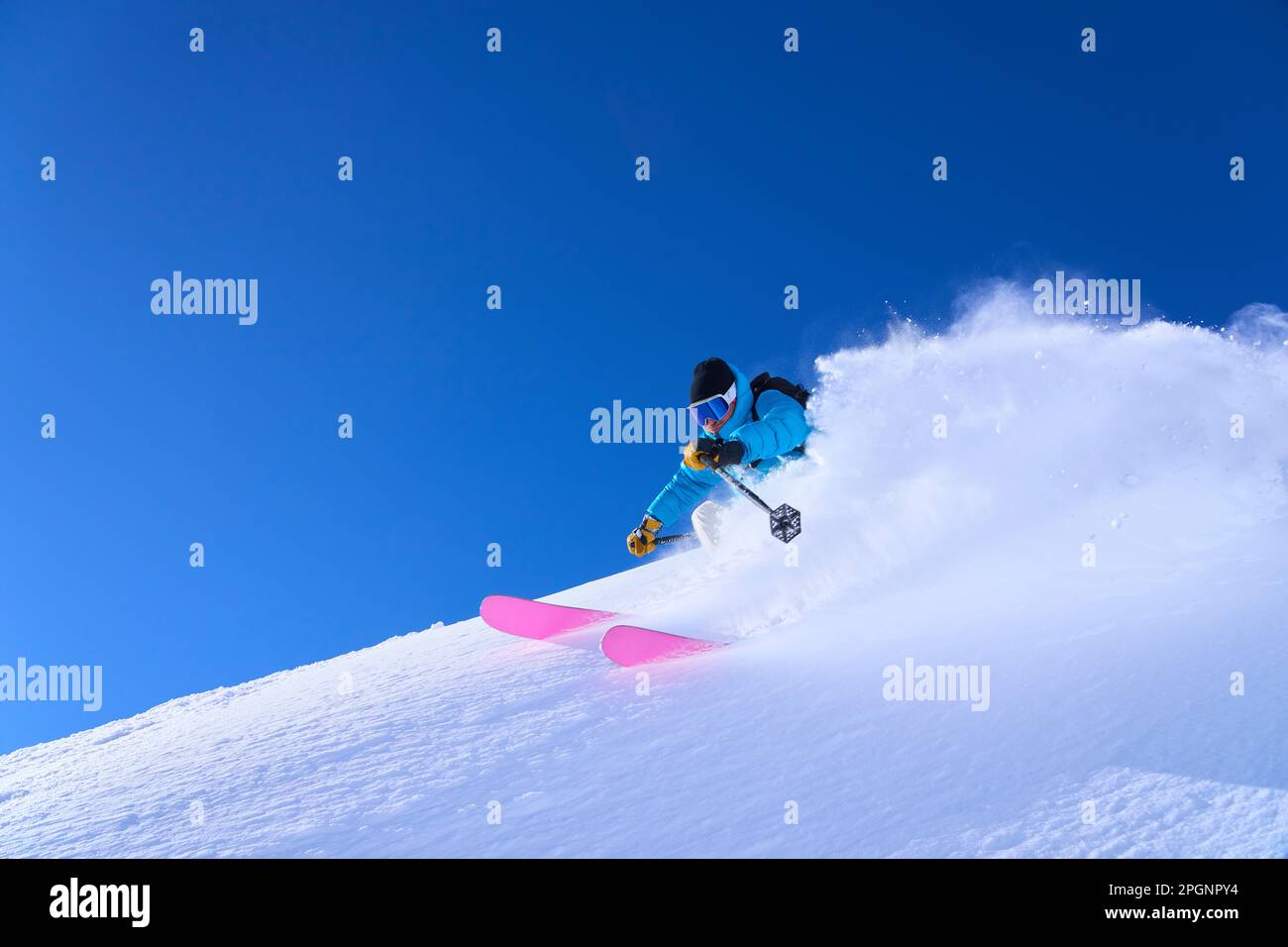 Man skiing downhill on snow under blue sky Stock Photo