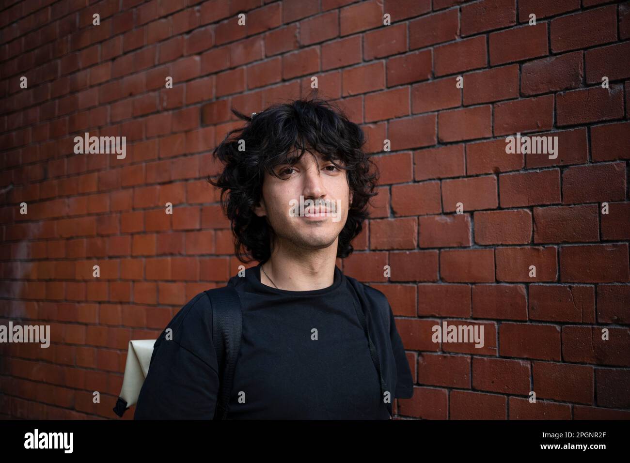 Smiling young man by brick wall Stock Photo
