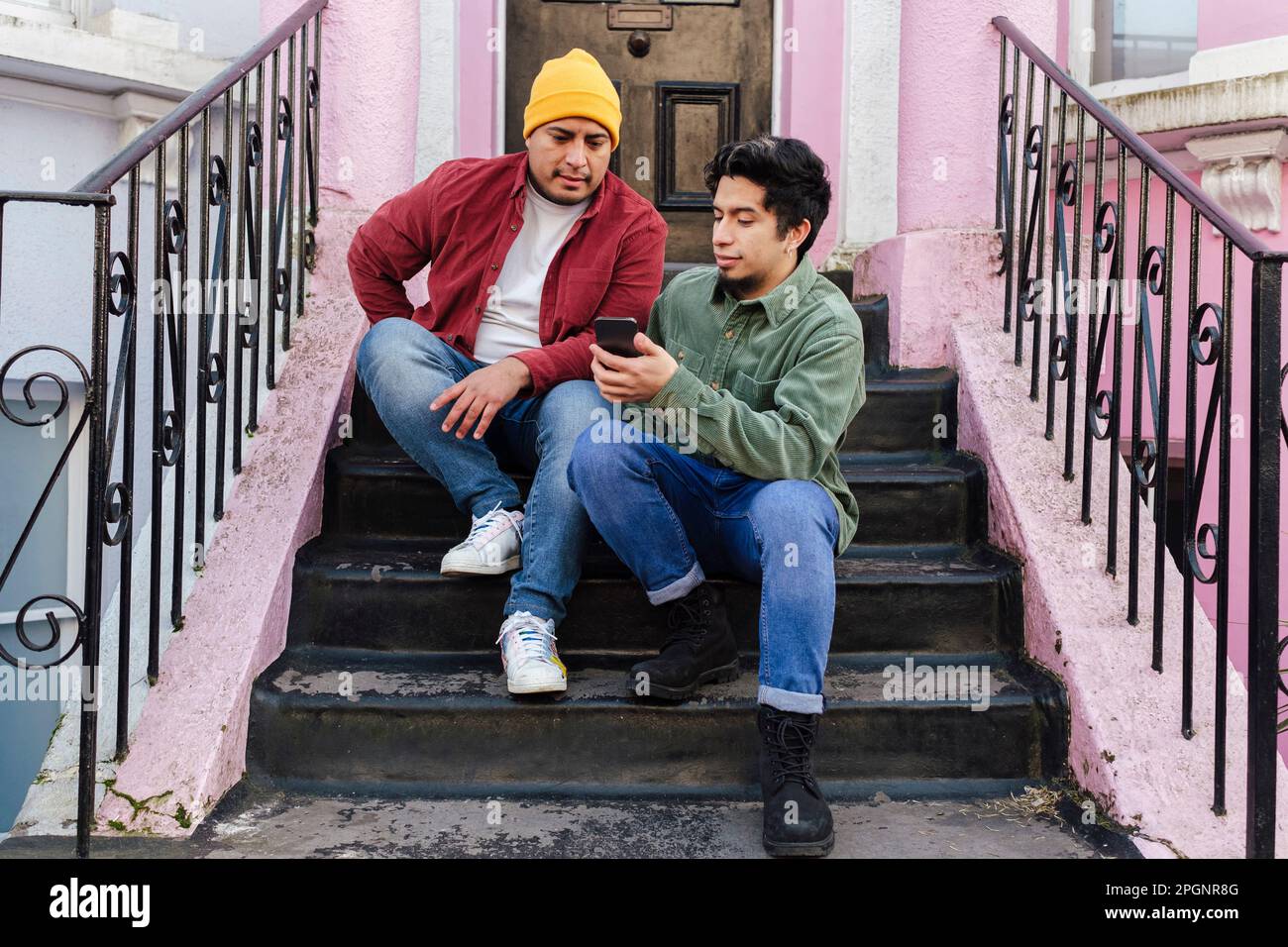 Man with brother using smart phone at steps Stock Photo