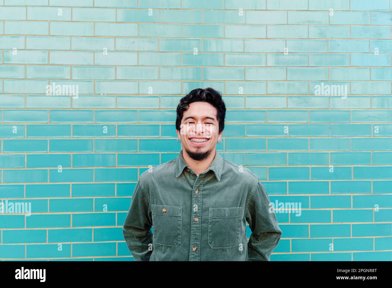Smiling young man standing in front of brick wall Stock Photo - Alamy