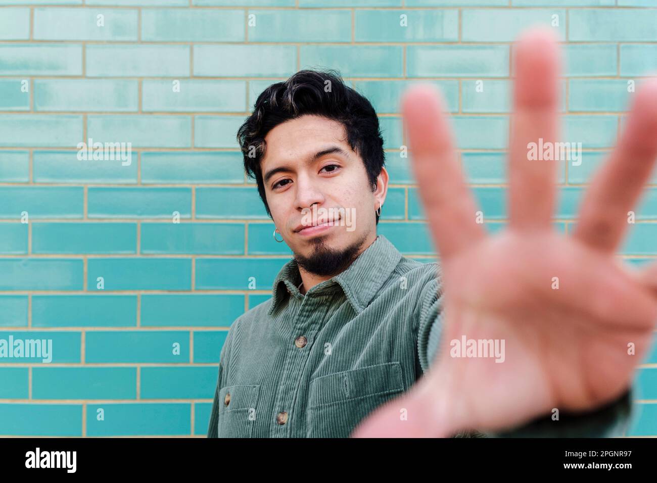 Young man stop gesturing in front of brick wall Stock Photo