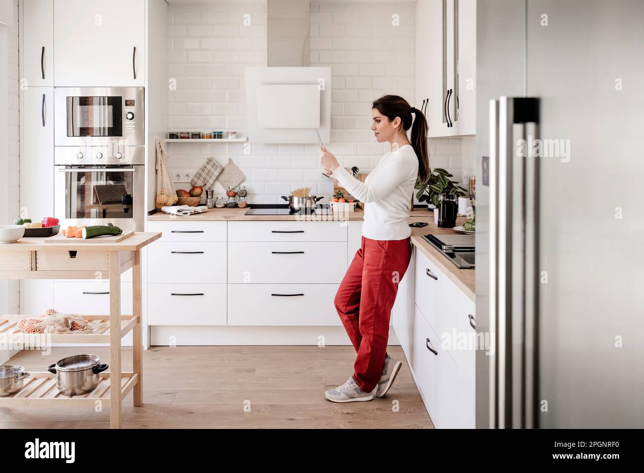 Woman using tablet PC standing in kitchen Stock Photo