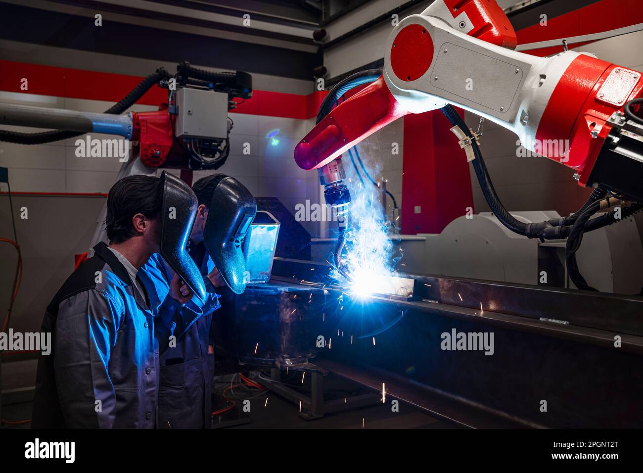 Engineers near robotic arm doing welding in industry Stock Photo Alamy