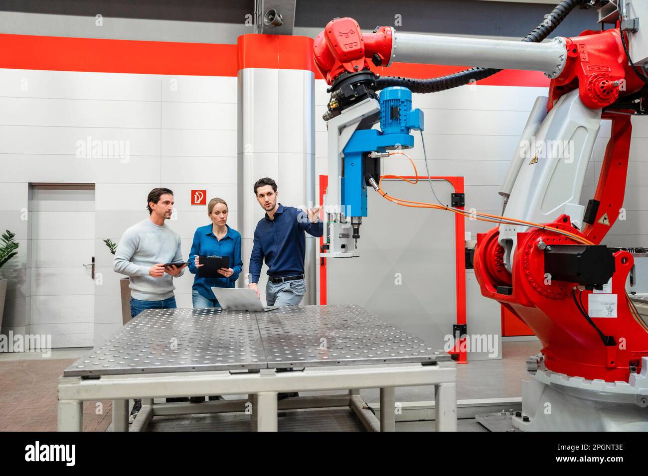 Colleagues examining robots in factory Stock Photo