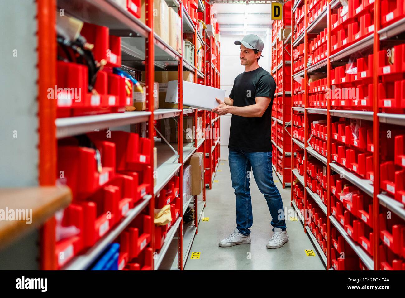 Warehouse Worker Removing Box From Rack Standing In Factory Stock Photo