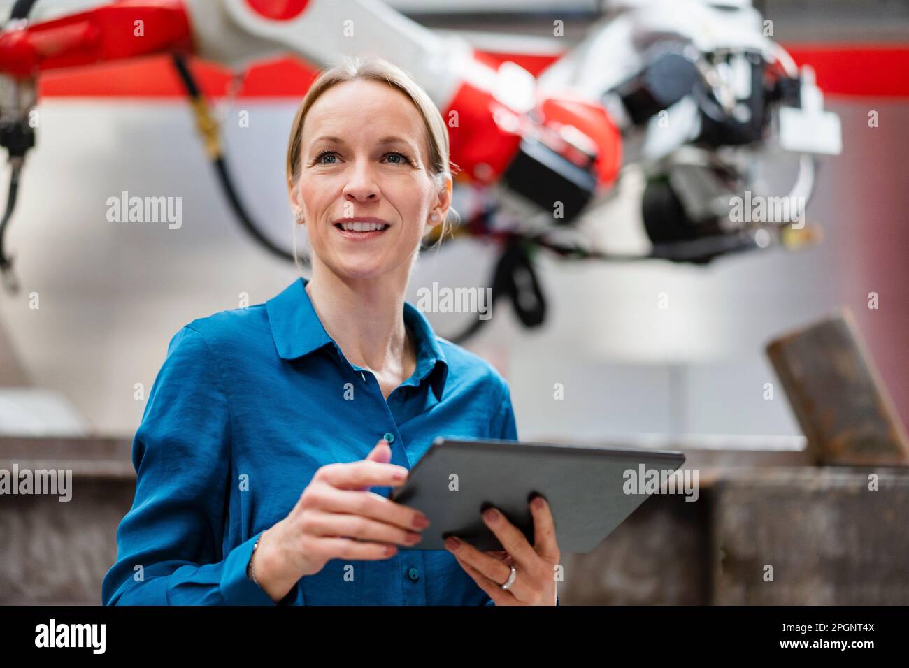 Contemplative engineer holding tablet PC in robot factory Stock Photo