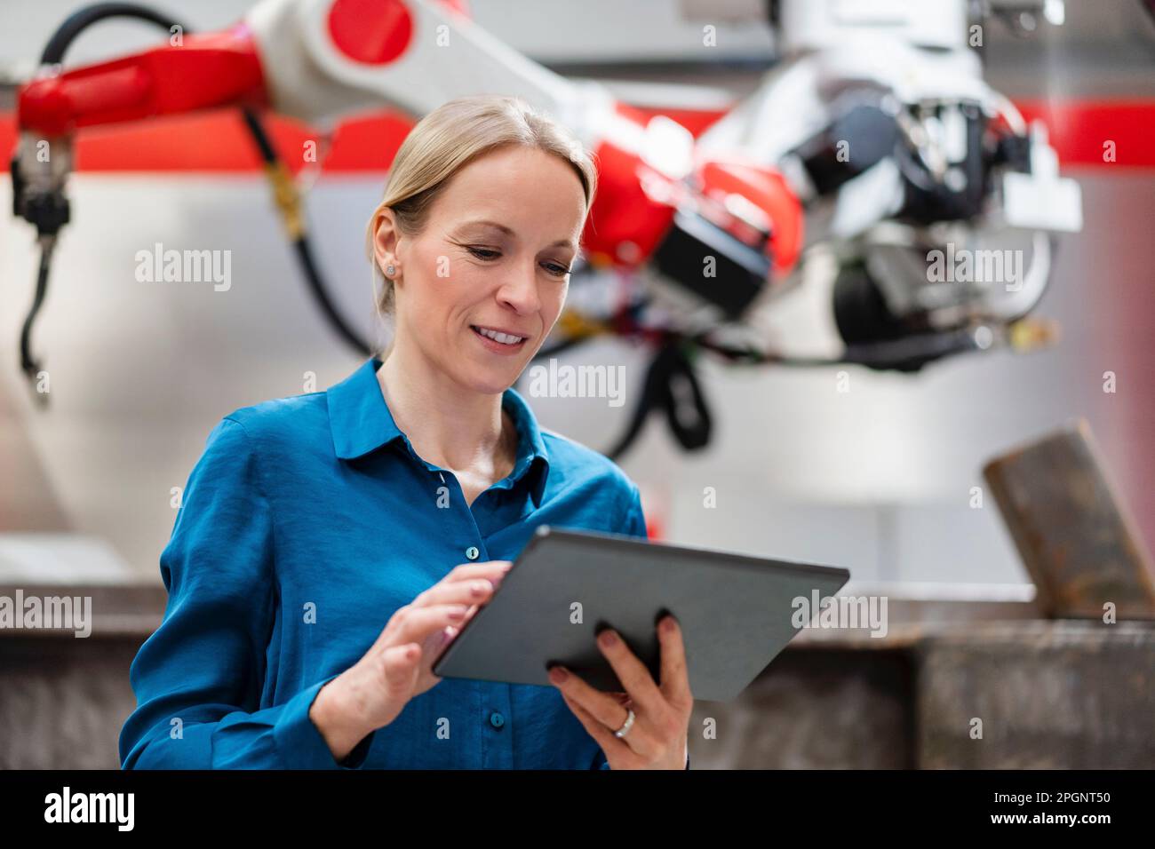 Technician using tablet PC in robot factory Stock Photo