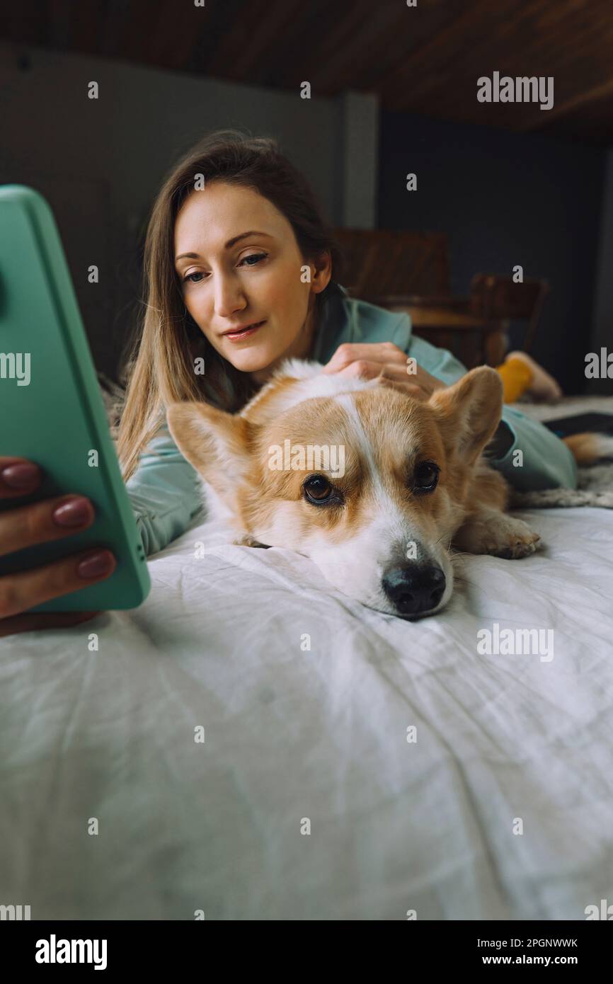Mature woman taking selfie with dog lying on bed at home Stock Photo