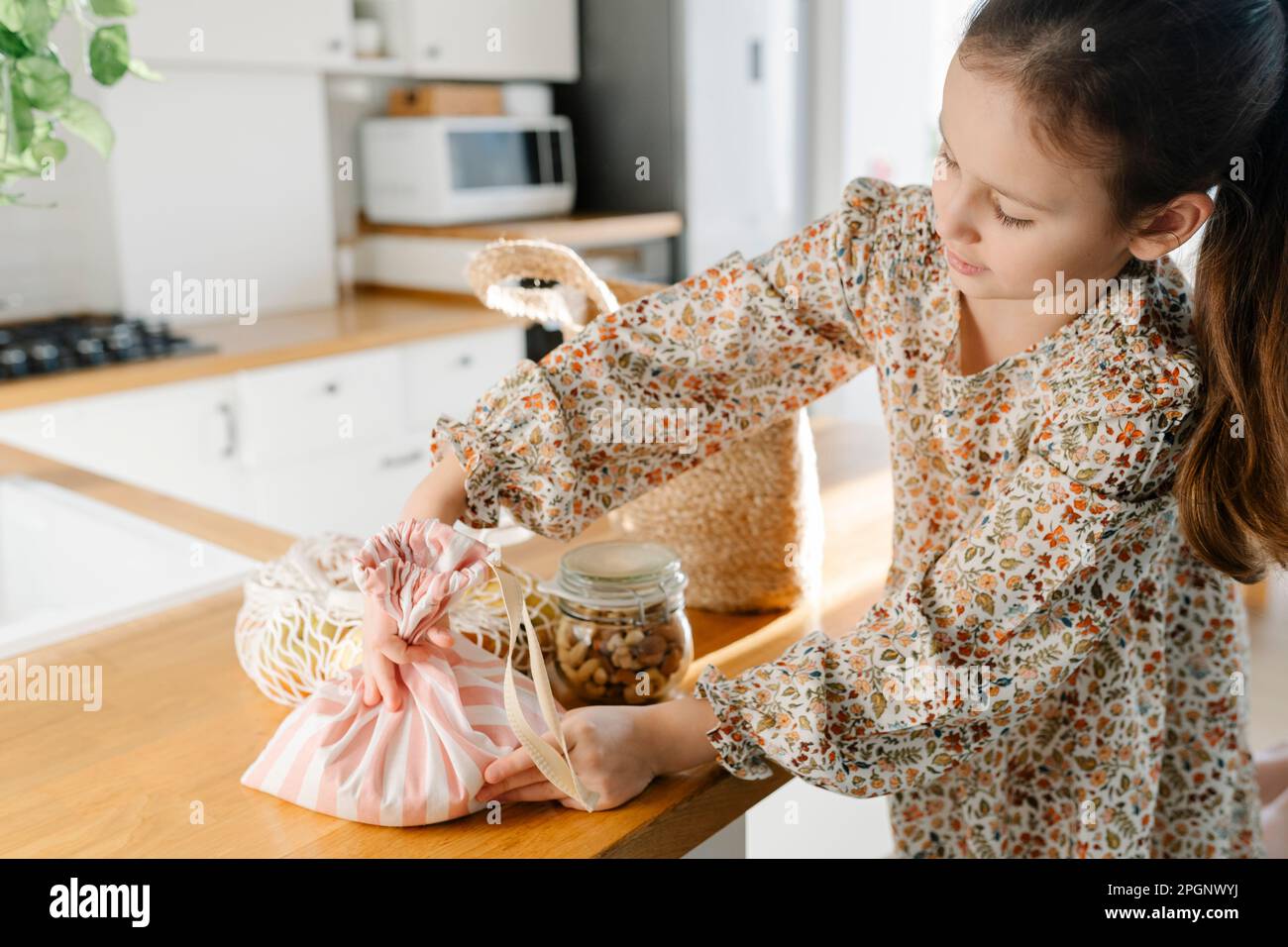 Girl with reusable bags on kitchen island at home Stock Photo
