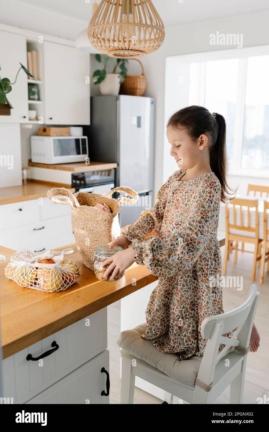 Girl unpacking groceries on kitchen island at home Stock Photo