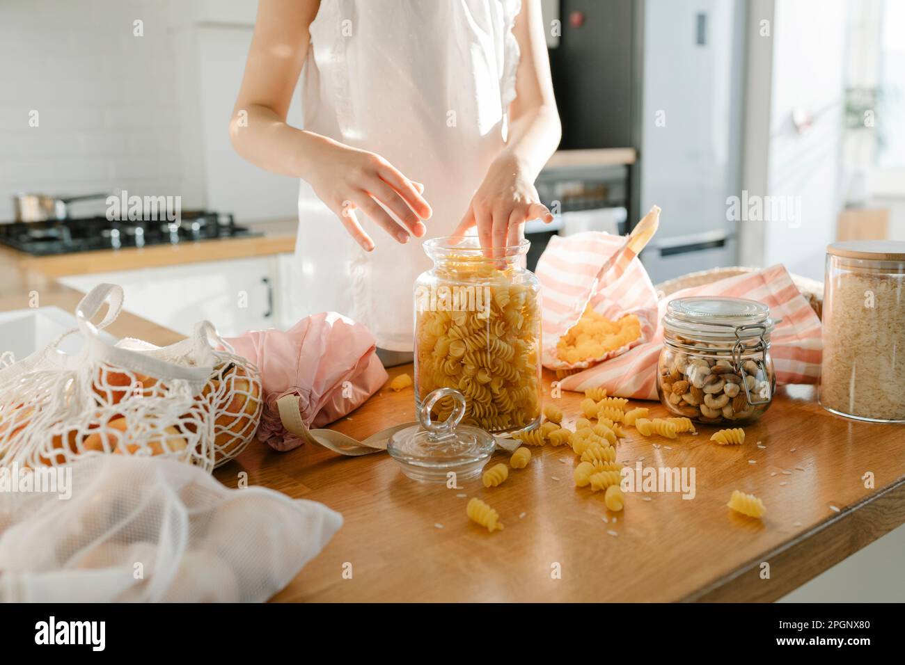Girl with pasta in glass jar on kitchen island at home Stock Photo