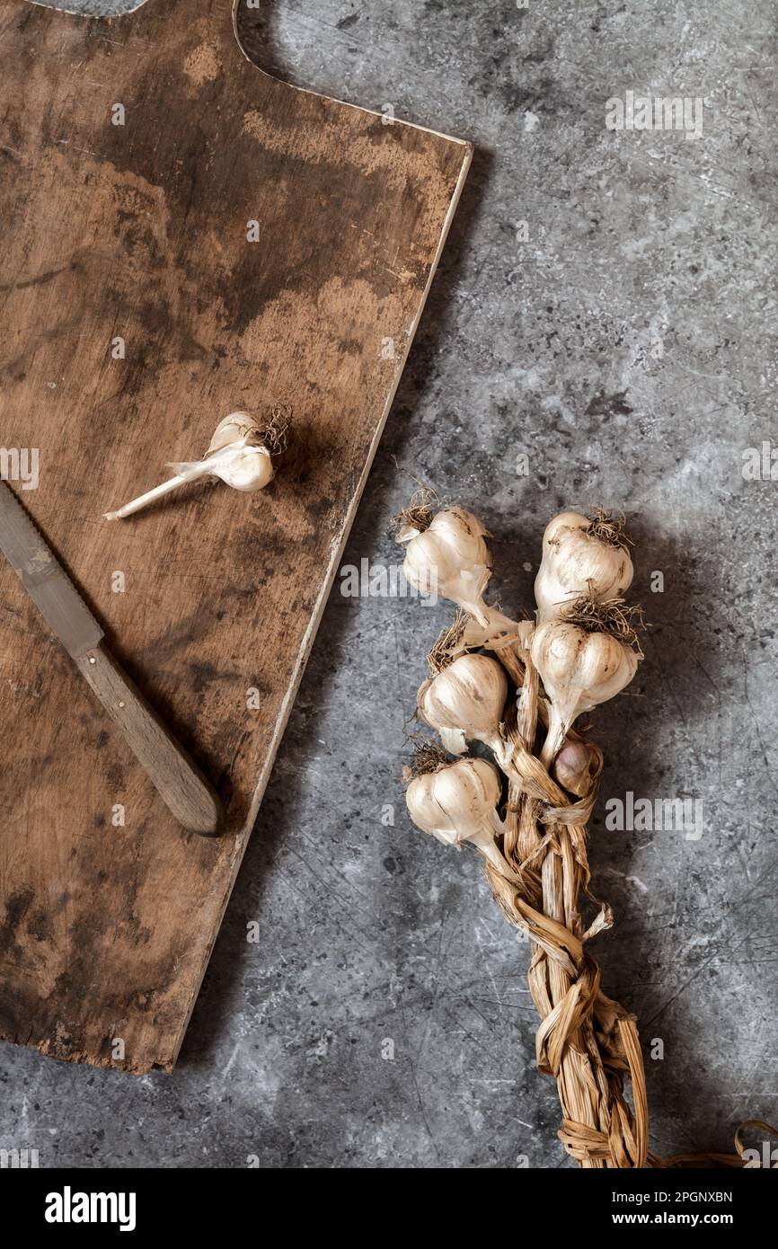 Raw garlic, cutting board and kitchen knife lying on gray surface Stock Photo