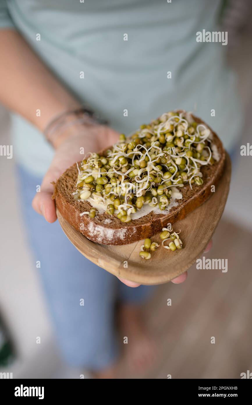 Woman holding sprout beans on toasted bread at home Stock Photo
