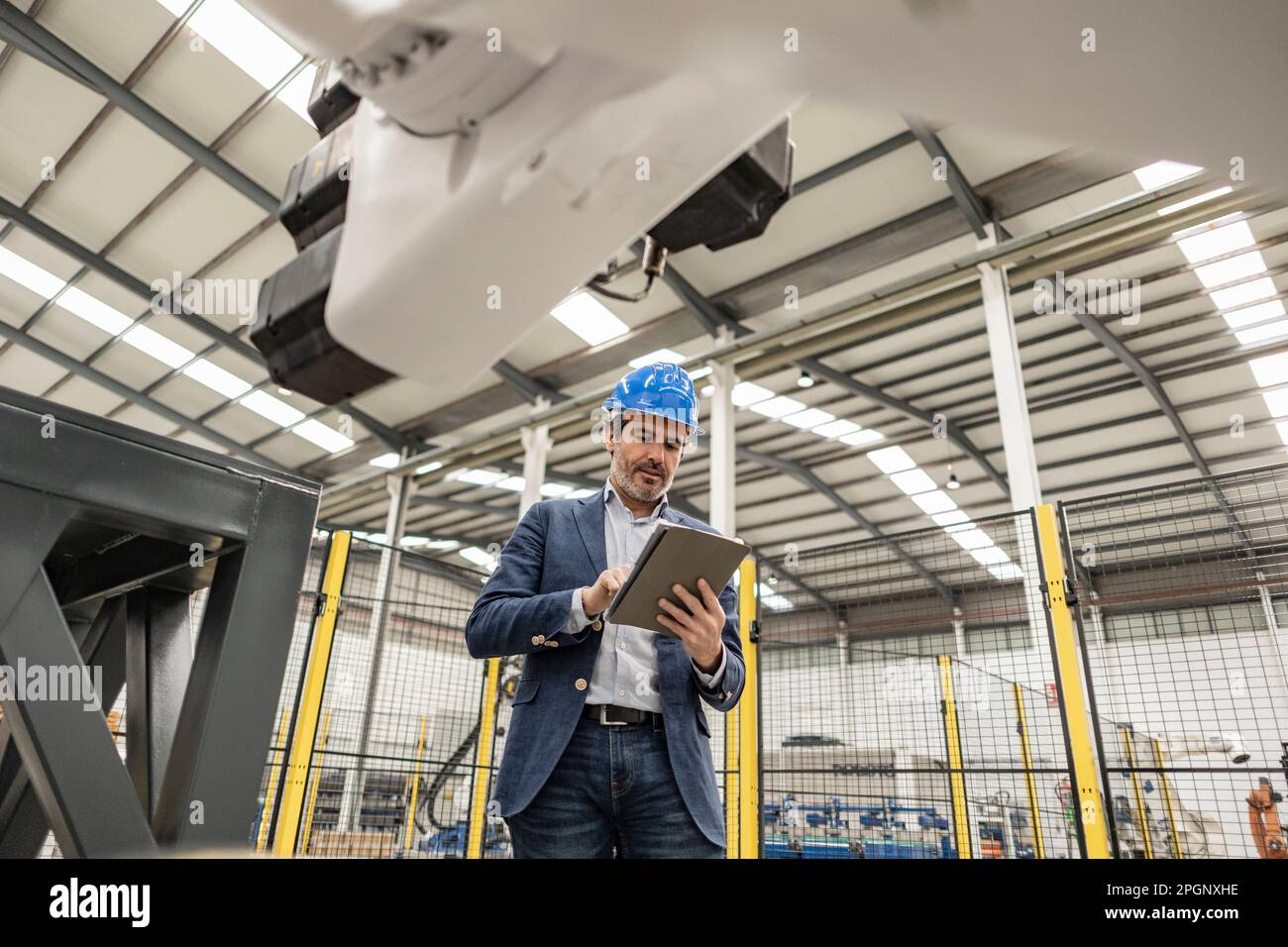 Engineer wearing hardhat using tablet PC in factory Stock Photo