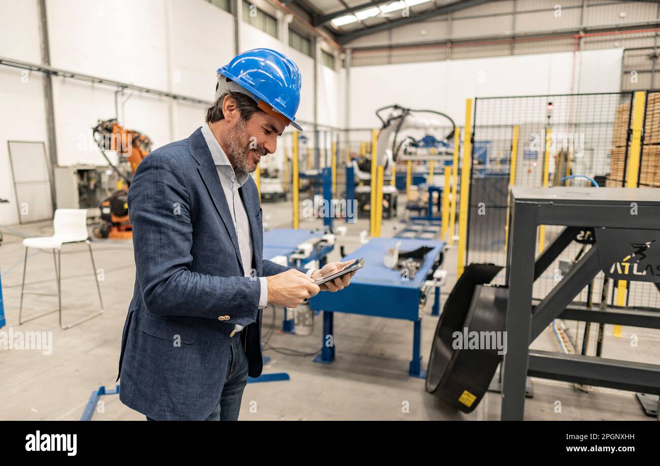 Engineer wearing hardhat using tablet PC at industry Stock Photo