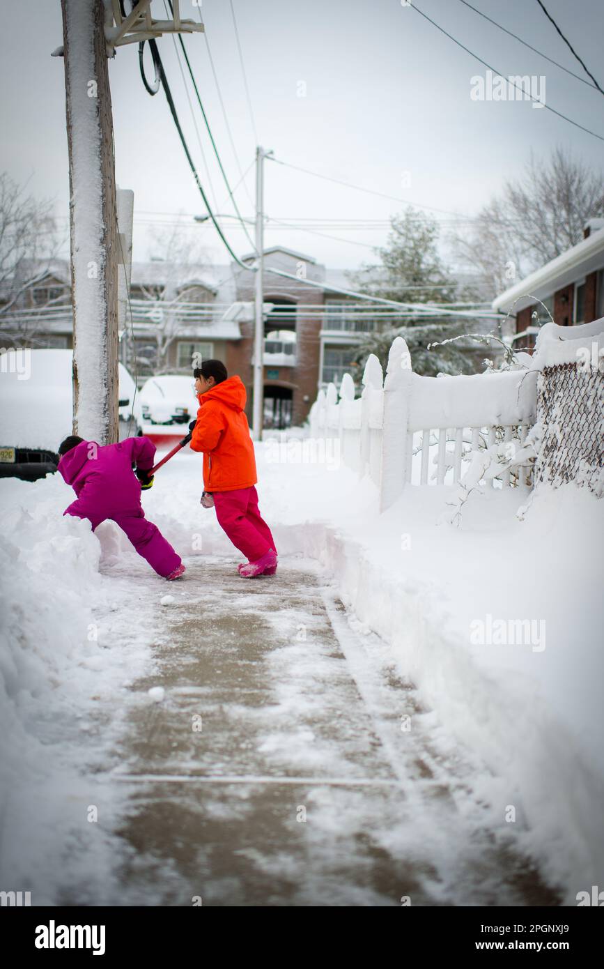 young asian girl shoveling snow after snow blizzard Stock Photo