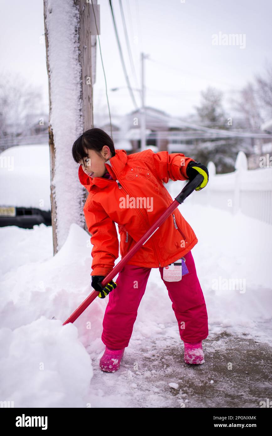 young asian girl shoveling snow after snow blizzard Stock Photo Alamy