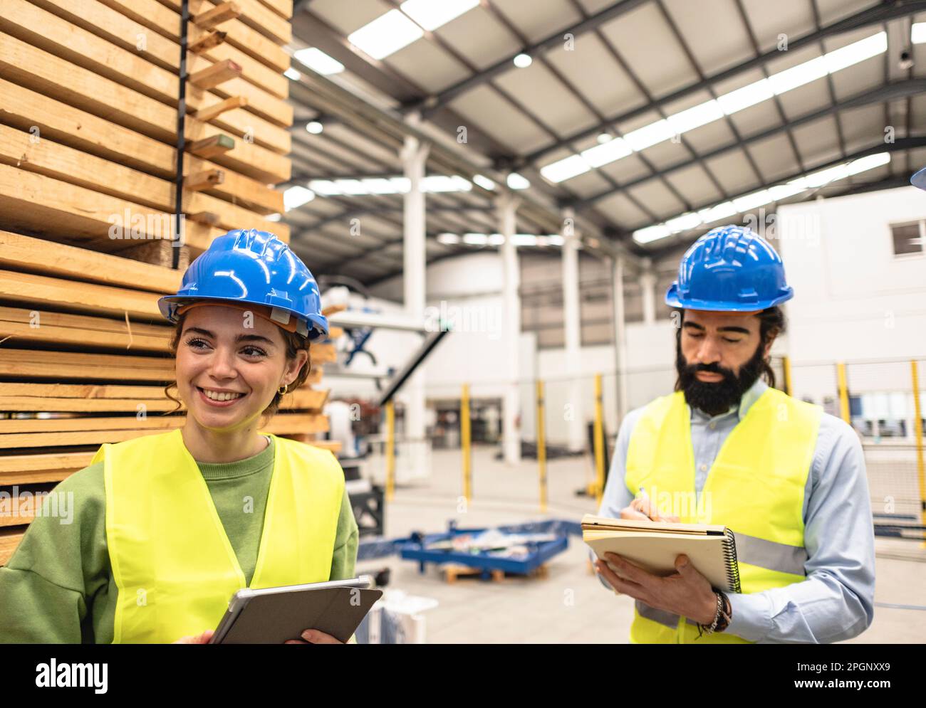 Smiling engineer with colleague making notes in factory Stock Photo